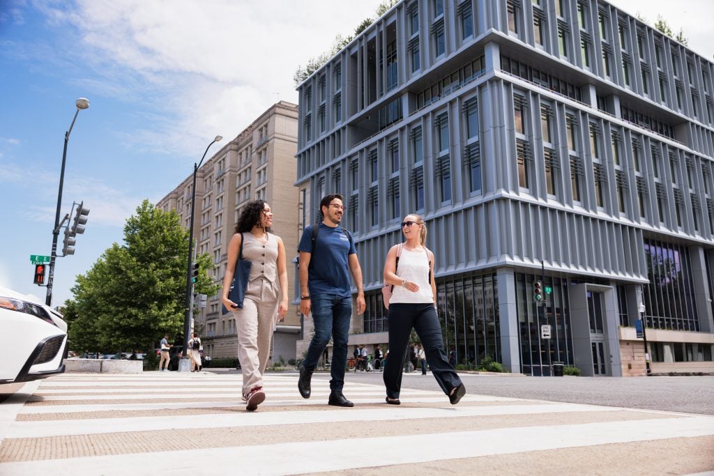 Three students on a crosswalk in front of a building on the Capitol Campus on a sunny day