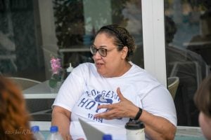 A woman wears glasses and a white T-shirt.