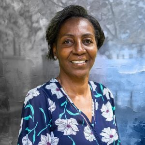 A woman with short black hair wears a shirt with flowers on it.