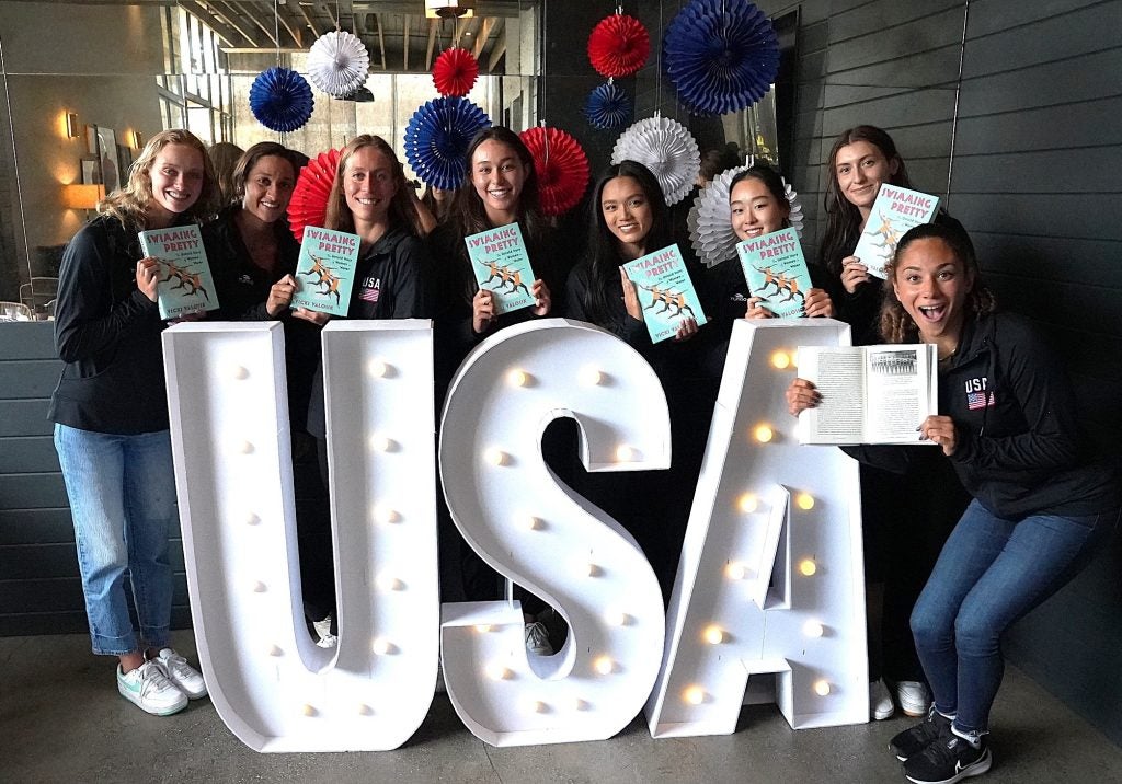 The U.S. artistic team poses with Vicki Valosik's book, "Swimming Pretty," and the letters "USA."