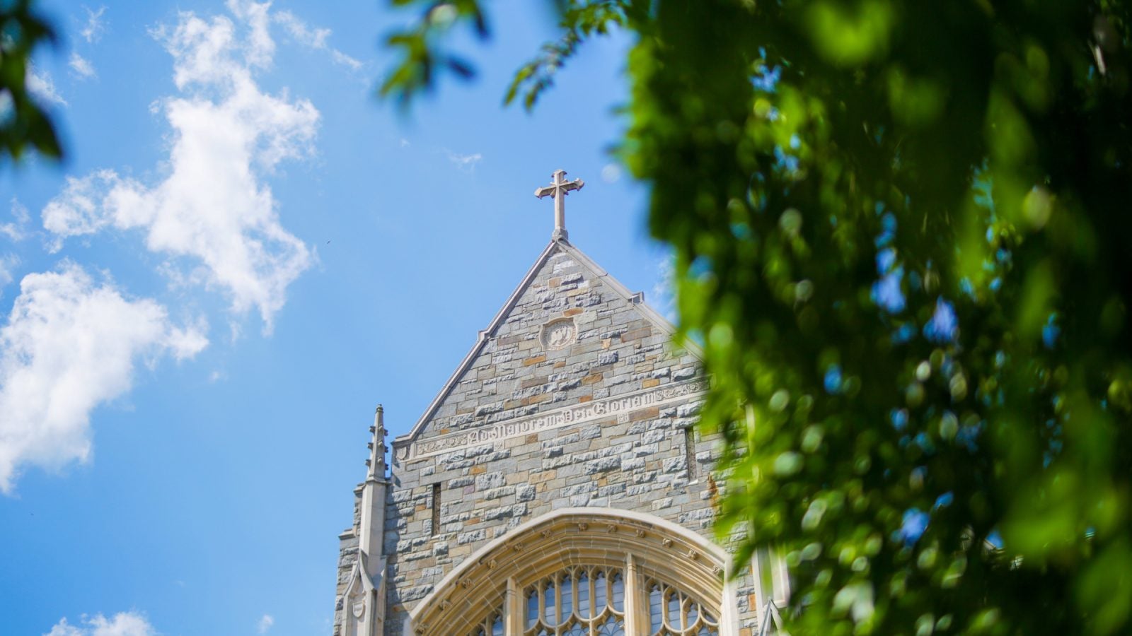 Stone cross against a blue sky on top of Georgetown University&#039;s White-Gravenor Hall