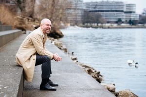 Uwe Brandes sitting on some steps by the water on an overcast day