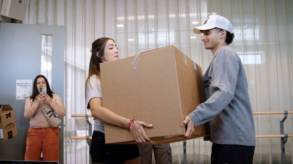 A young man and woman lift a large box