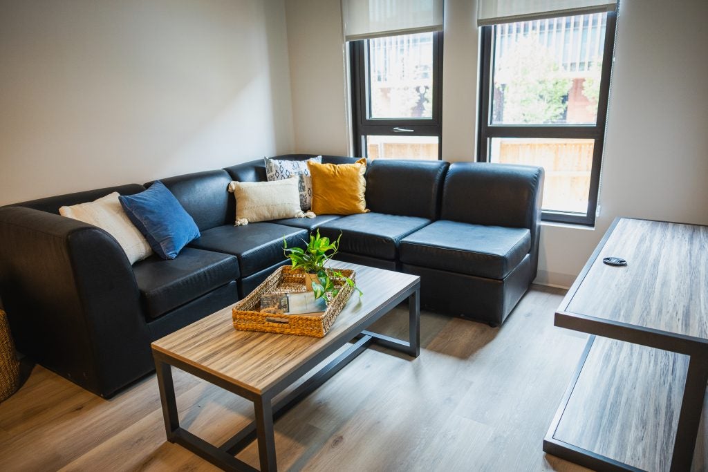 An apartment living room with a couch and two windows and a coffee table.