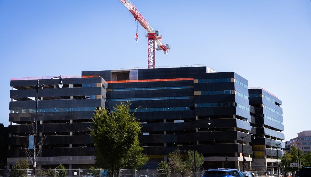 A building in downtown DC with a crane at the top.