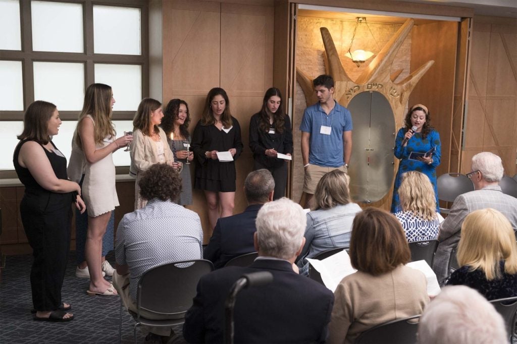 Students standing in Makom by the ark as Rabbi Ilana speaks