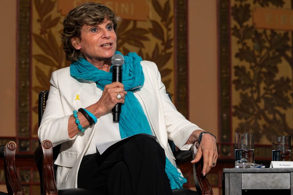 A woman with a blue scarf speaks into a mic on a stage at Georgetown.