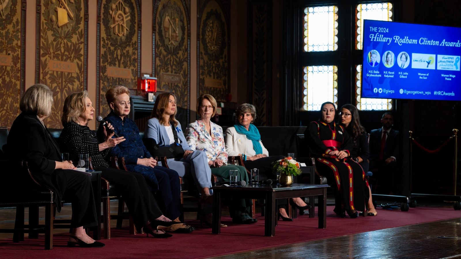 A group of female panelists discuss an issue on the stage at Georgetown.