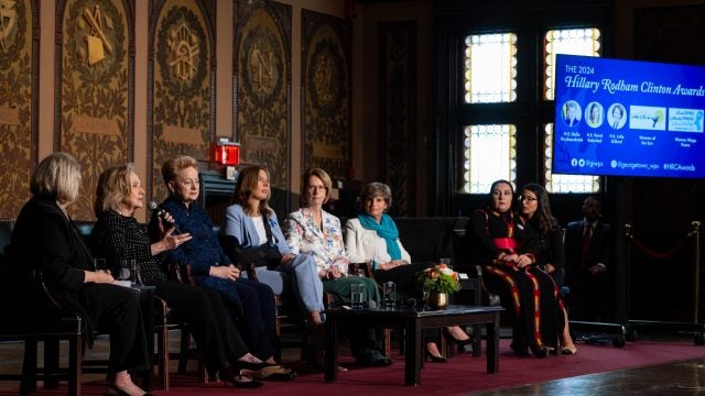 A group of female panelists discuss an issue on the stage at Georgetown.