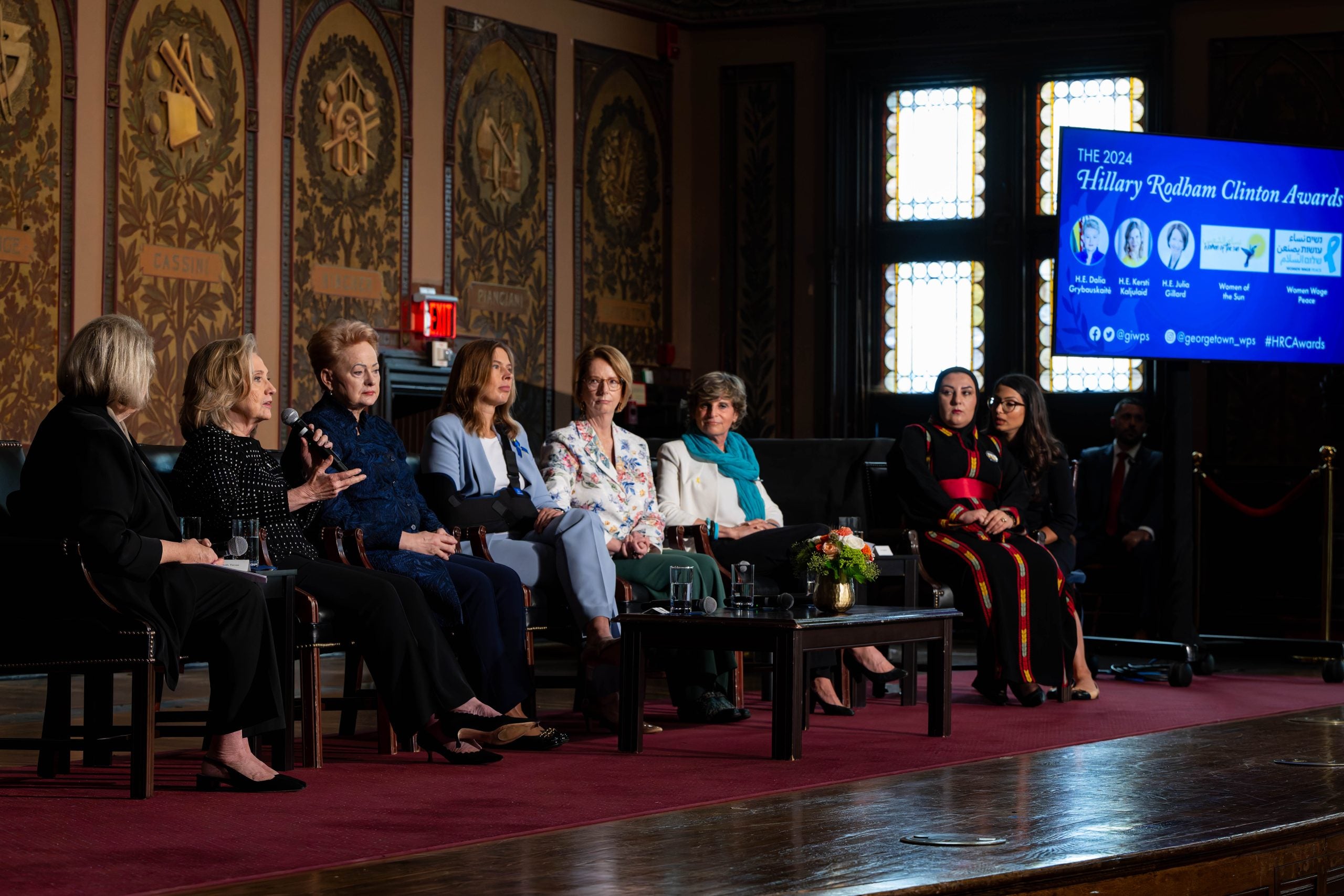 A group of female panelists discuss an issue on the stage at Georgetown.