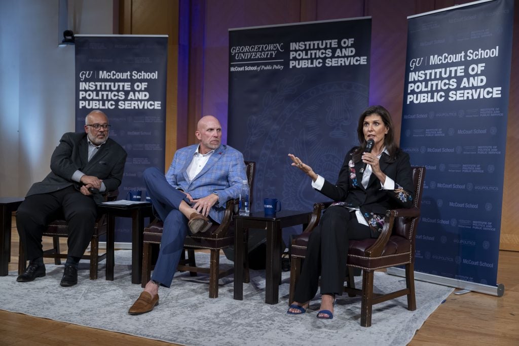 Haley on stage with two other men while speaking into a mic