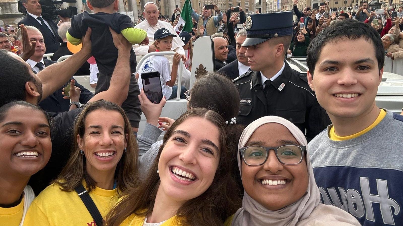 Alejandra with Georgetown students in a crowd with Pope Francis in the background