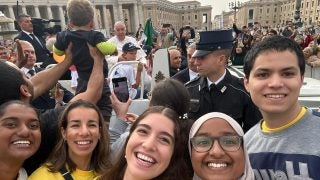 Alejandra with Georgetown students in a crowd with Pope Francis in the background