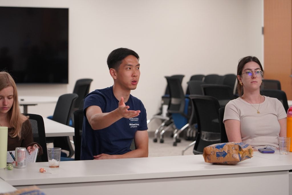 A young Asian man speaks while students listen