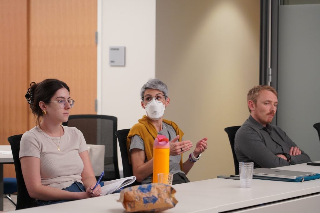 Merivaki speaks in a room while wearing a white mask