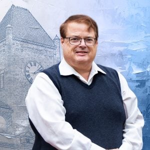 A man in a vest and glasses stands with his hands folded in front of him. Behind him is a graphic image of a clocktower.