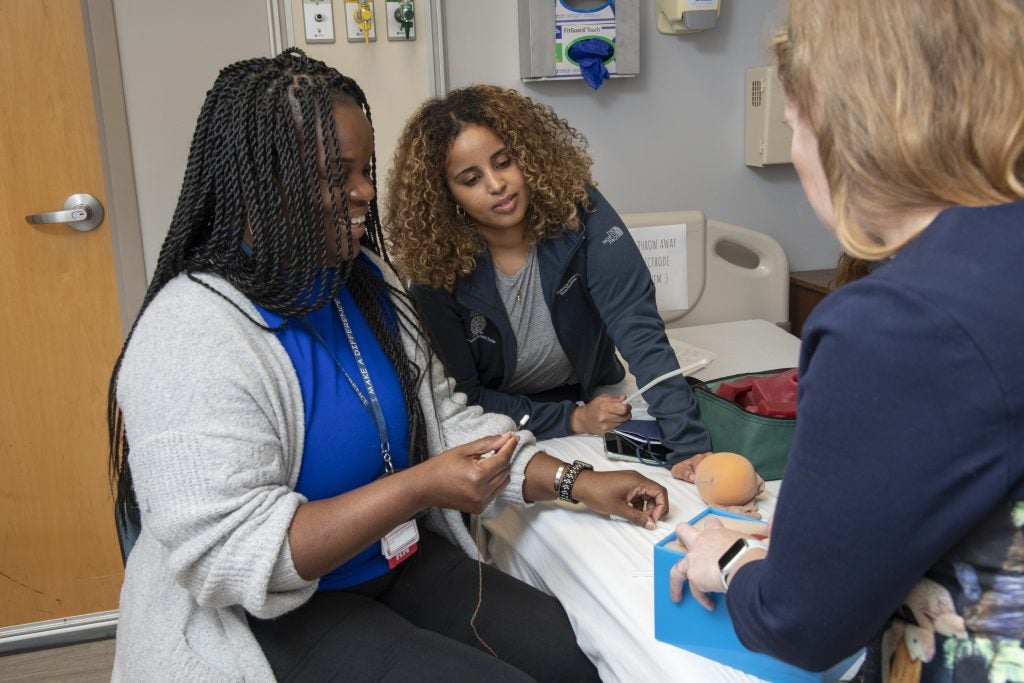 Two nursing students care for a patient.