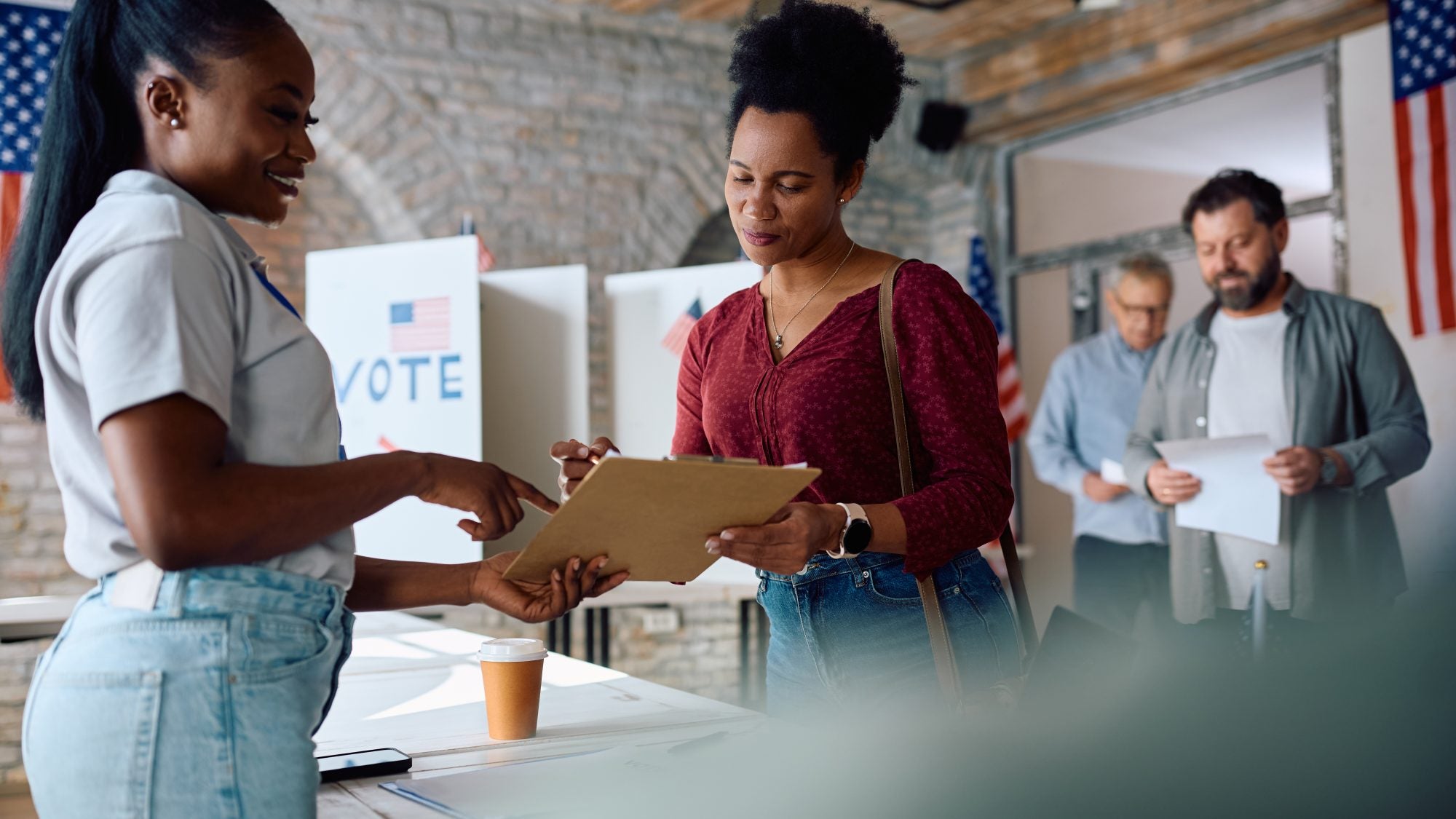 African American woman signing up to vote at polling place during US elections.