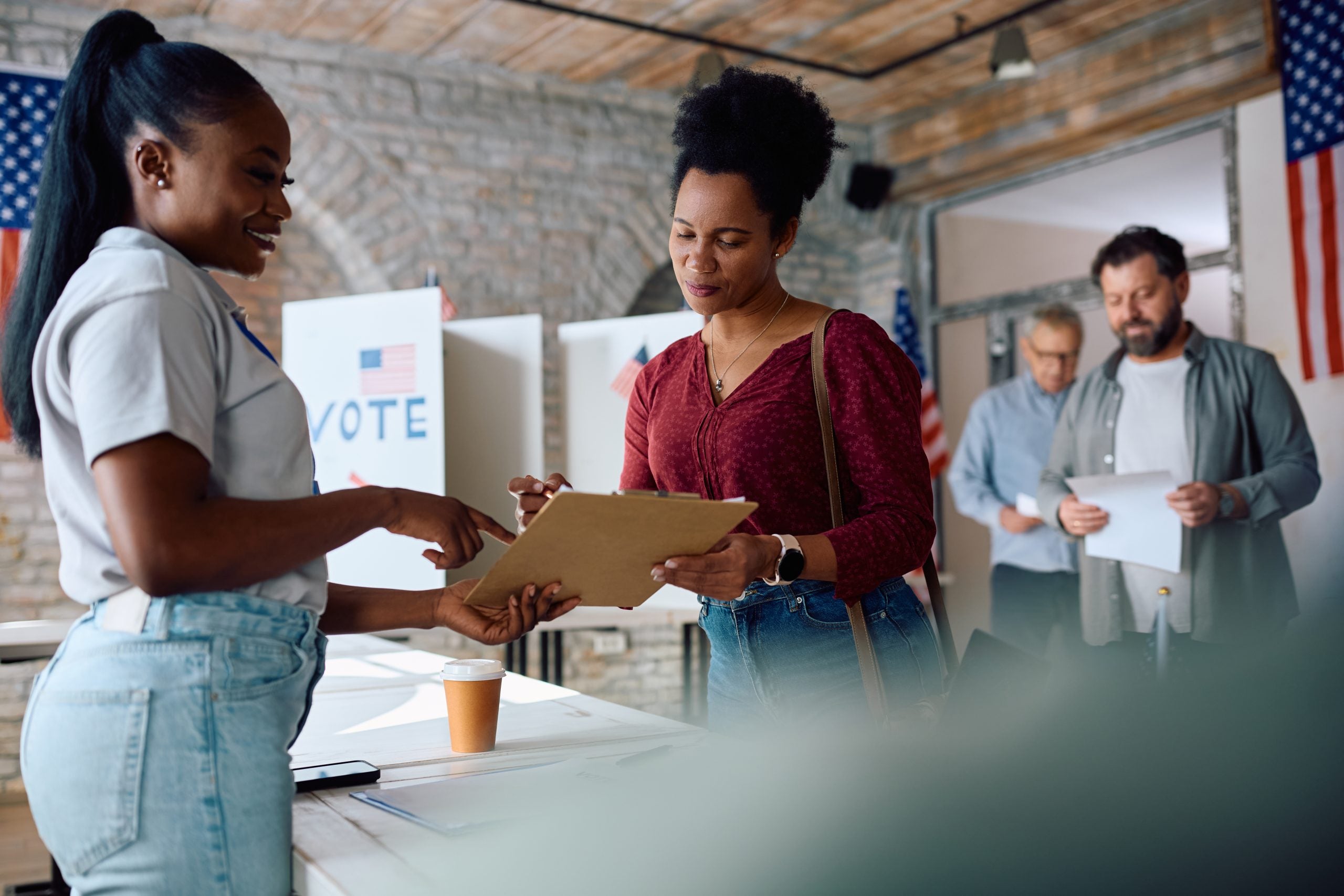 African American woman signing up to vote at polling place during US elections.