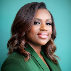 A woman with brown curled hair and a green shirt smiles.