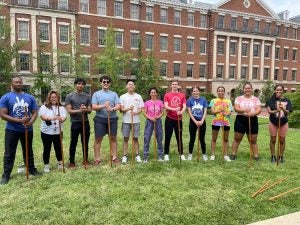 A group of students with sticks on a lawn.