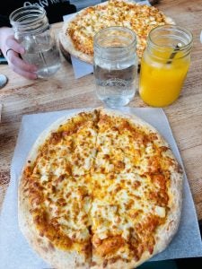 A cheese pizza with an orange drink