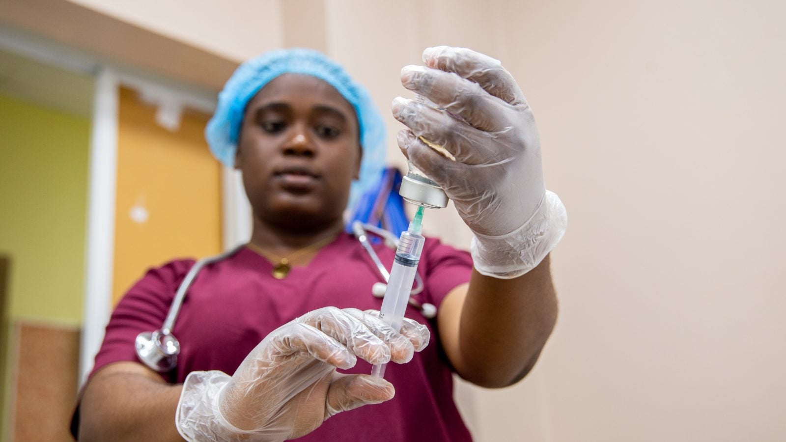 A nurse holds up a shot with gloves.