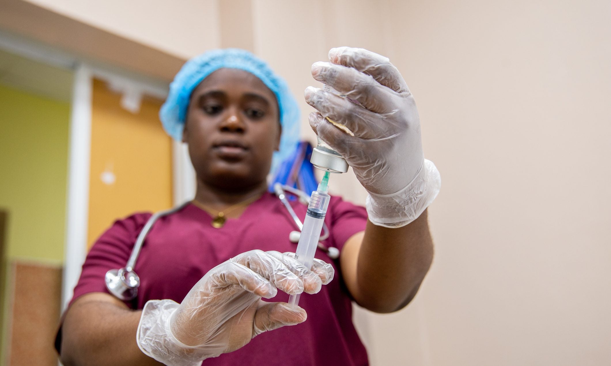 A nurse holds up a shot with gloves.