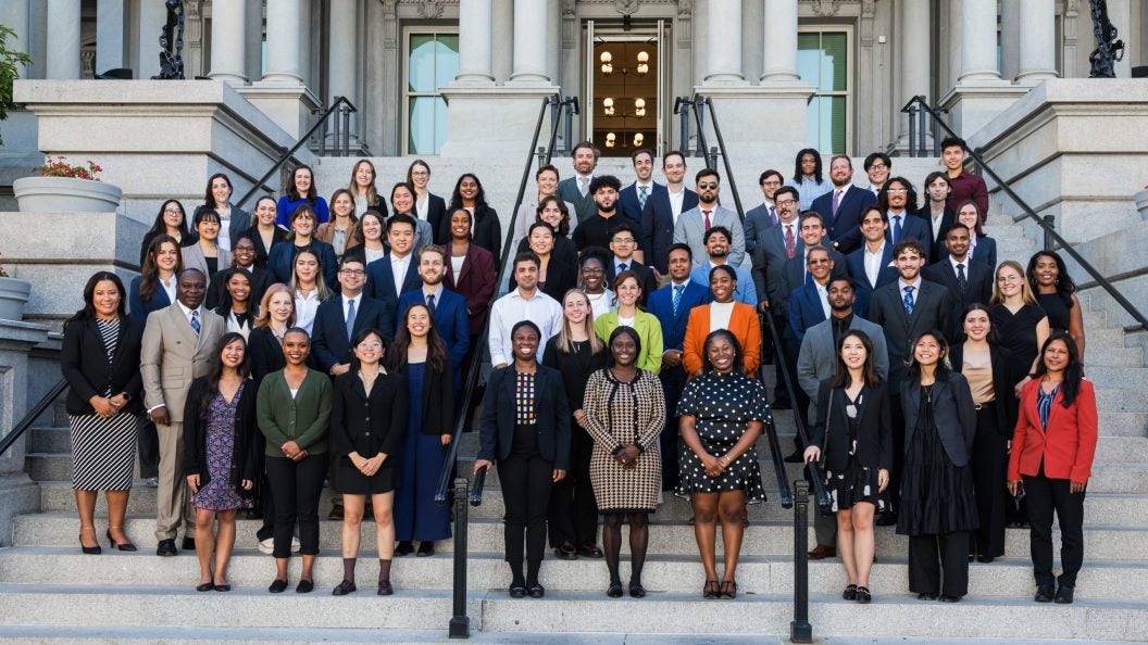 A group of men and women stand on the steps of a building.