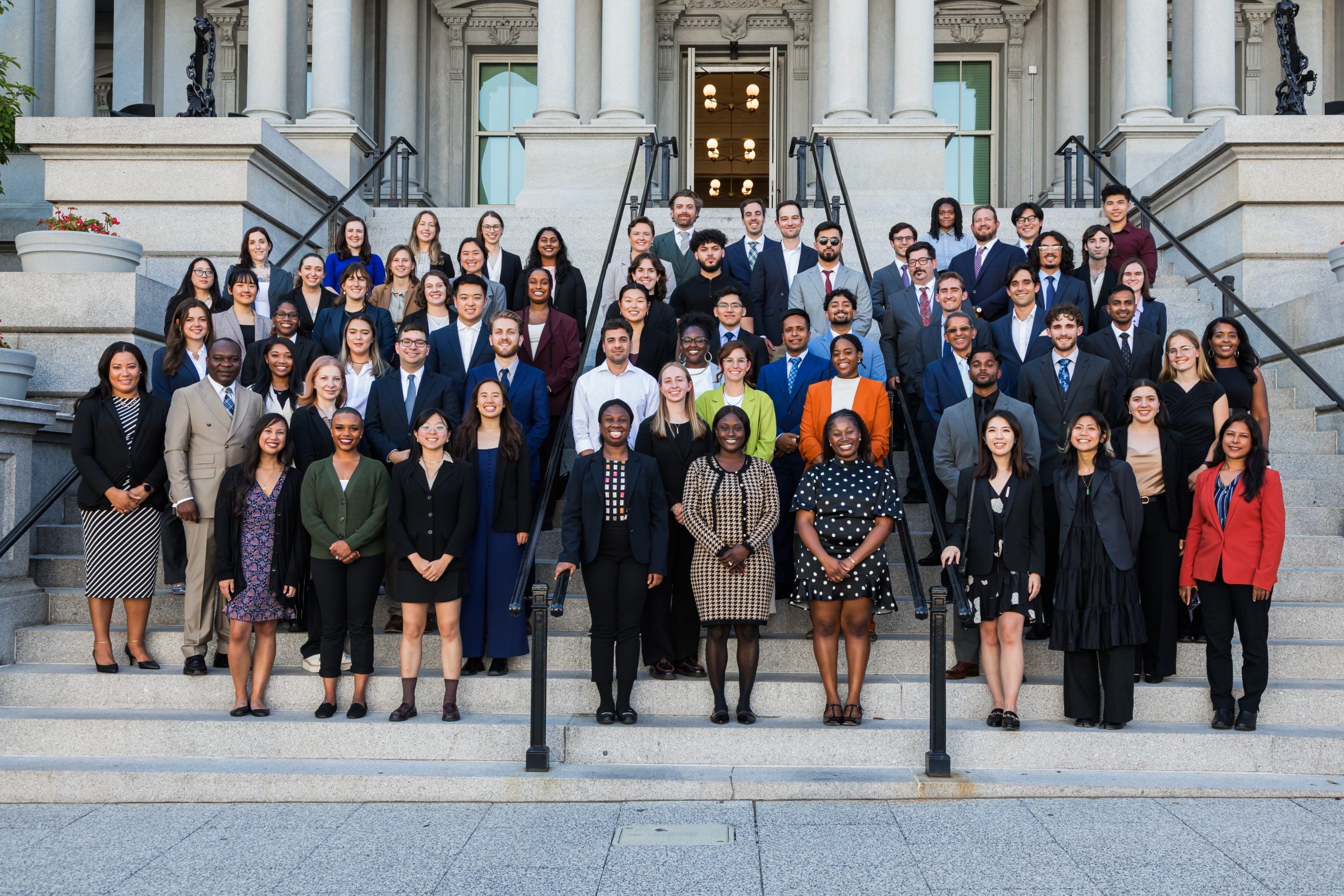 A group of men and women stand on the steps of a building.