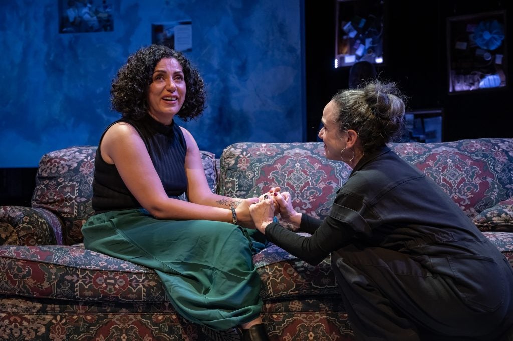 Two women hold hands while performing on a stage in DC.