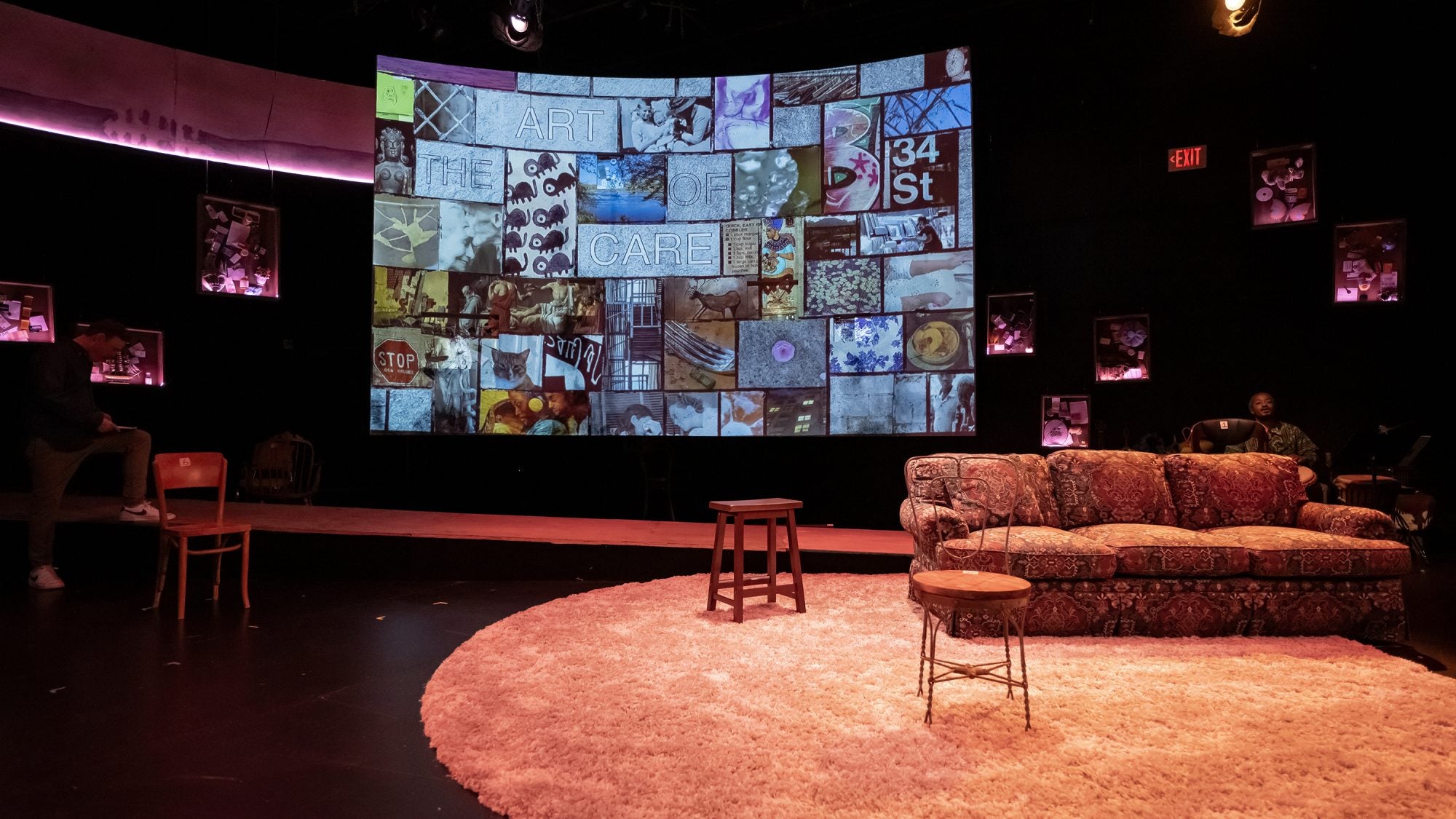 A stage is set with a couch on a carpet in front of a screen filled with mosaic images.