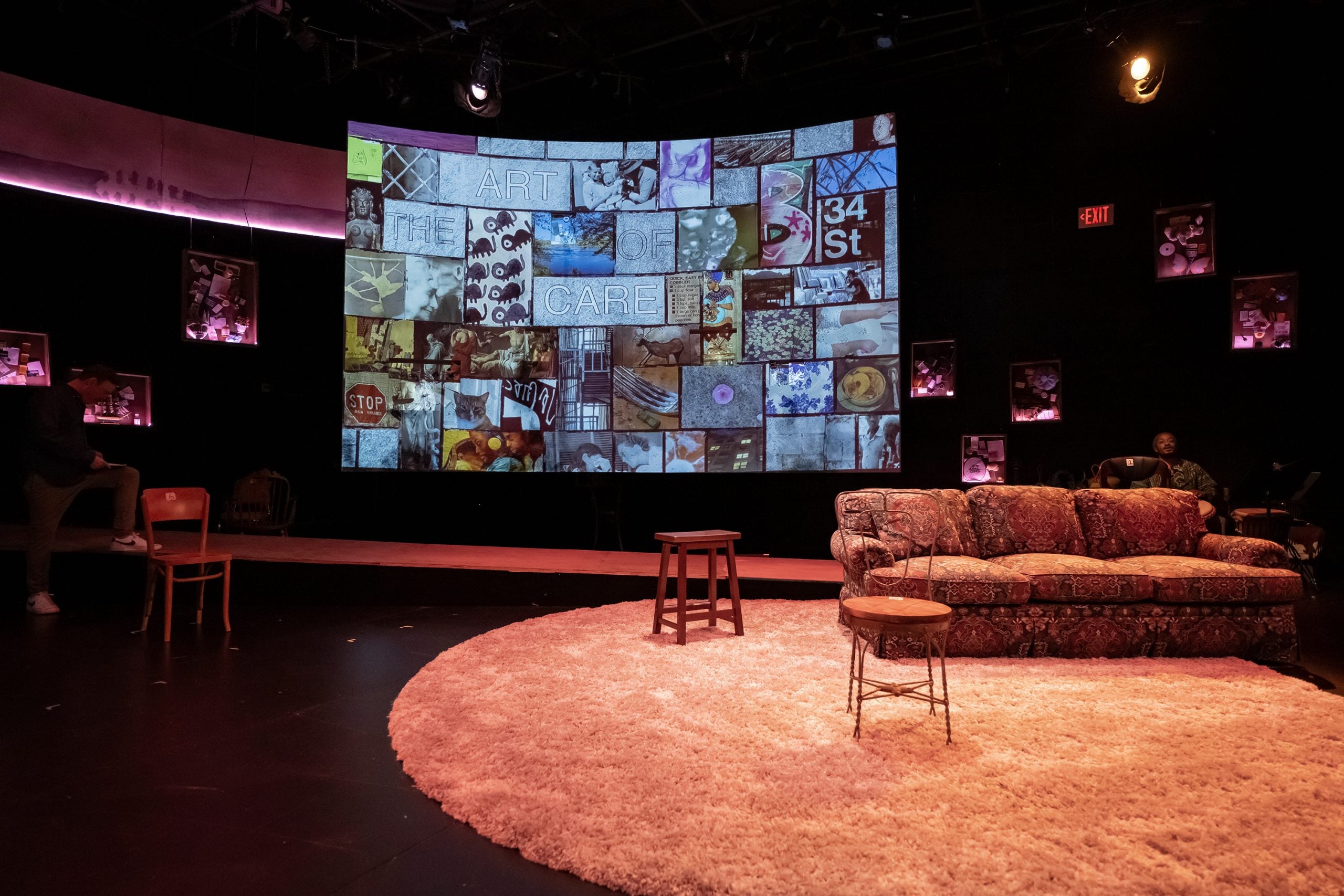 A stage is set with a couch on a carpet in front of a screen filled with mosaic images.