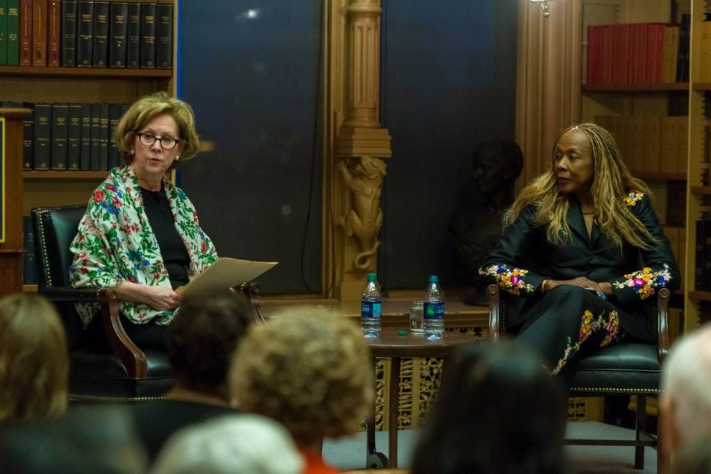 Two women sit on chairs as panelists.