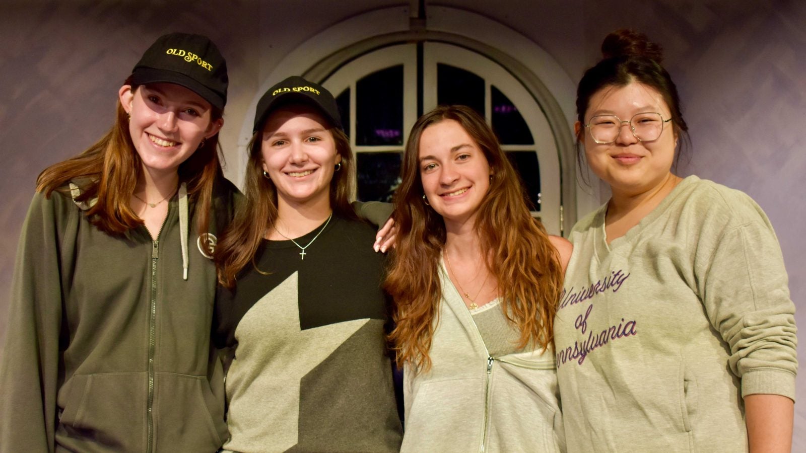 A group of female students wearing different shades of green pose together.