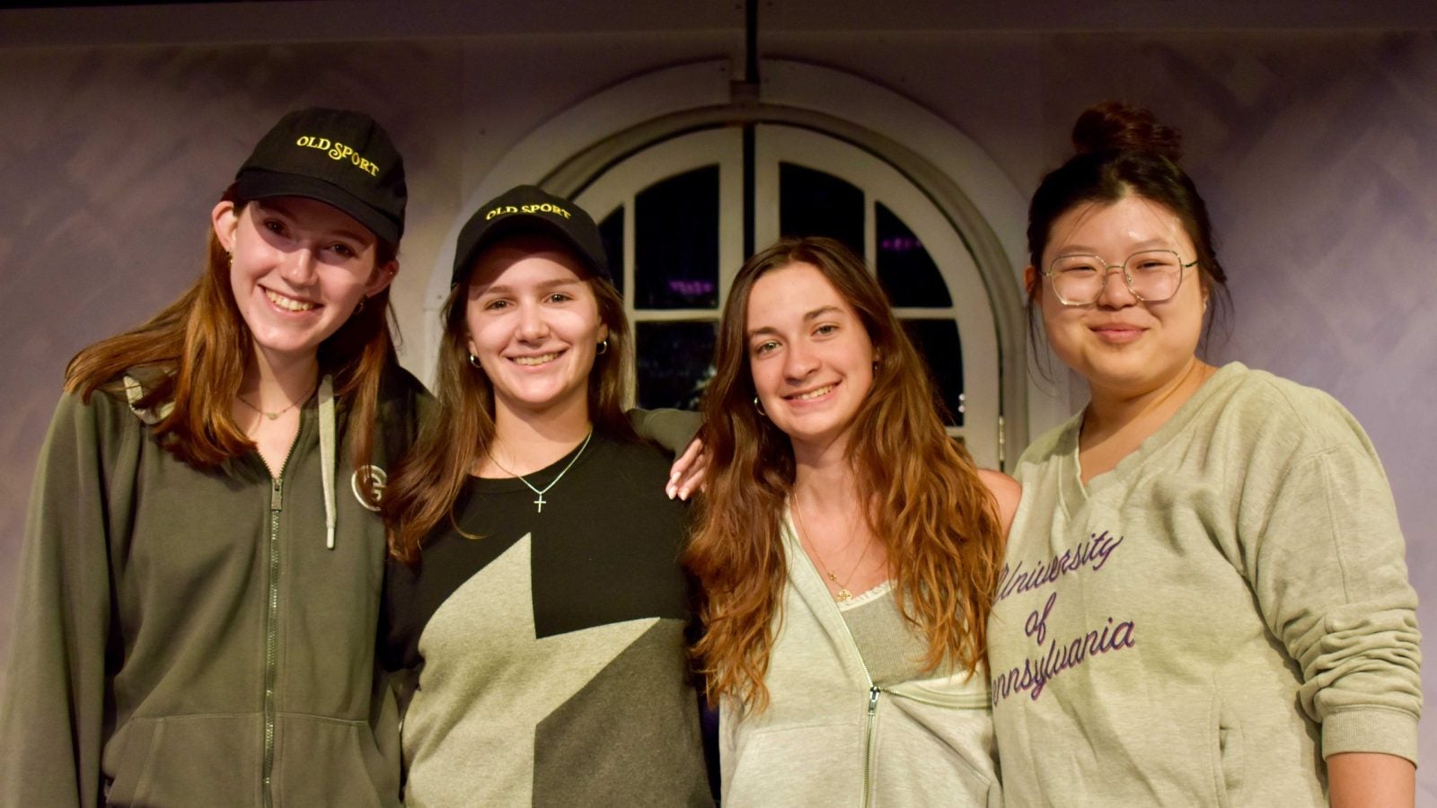 A group of female students wearing different shades of green pose together.