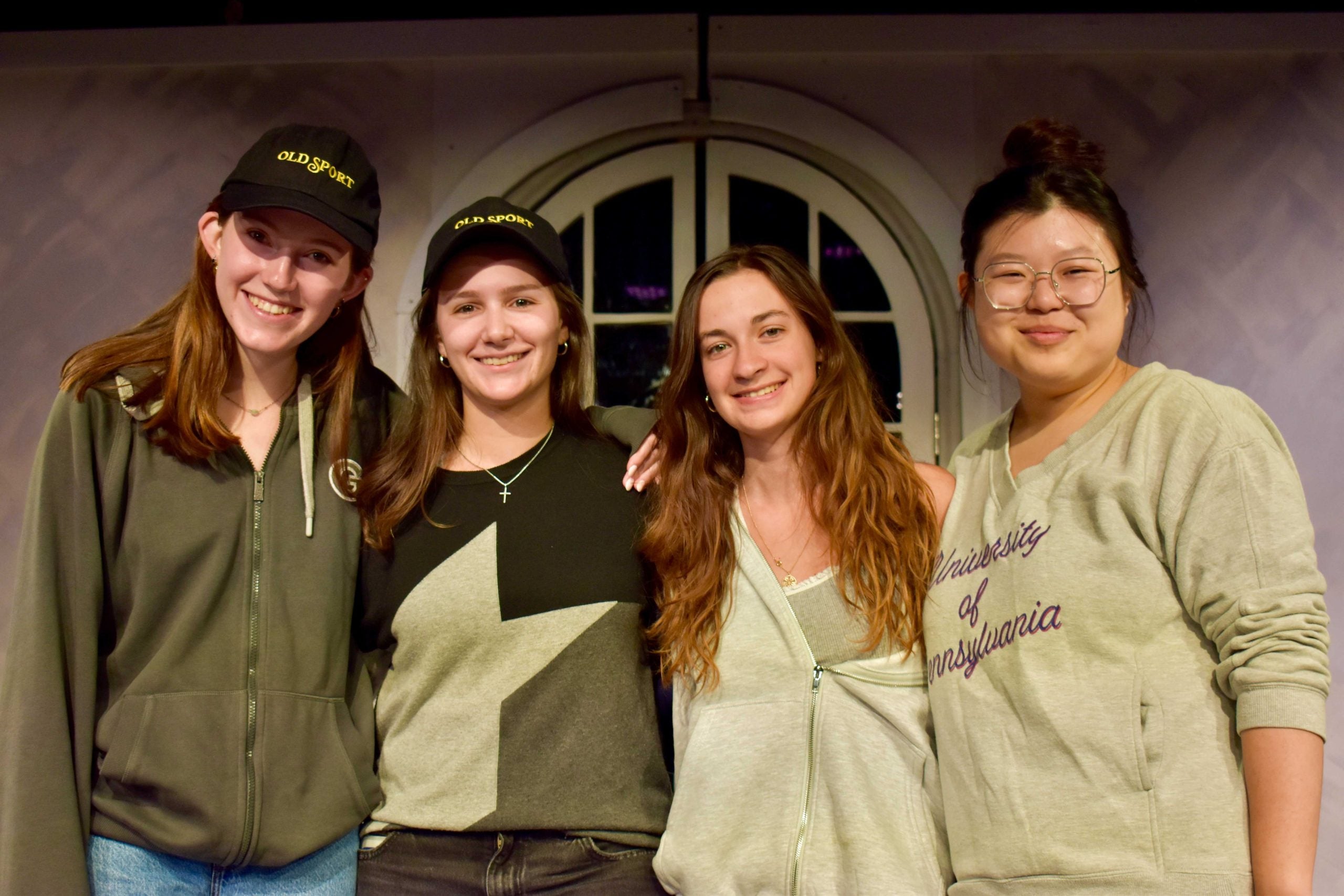 A group of female students wearing different shades of green pose together.