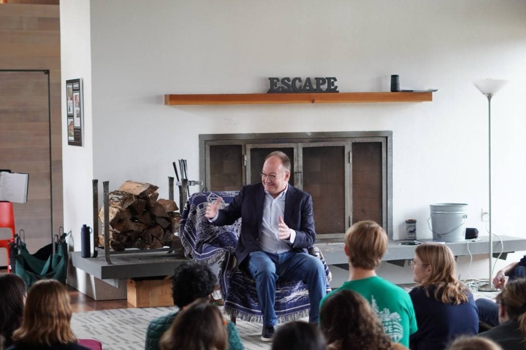 President DeGioia sits by a fireplace and speaks to a group of students.