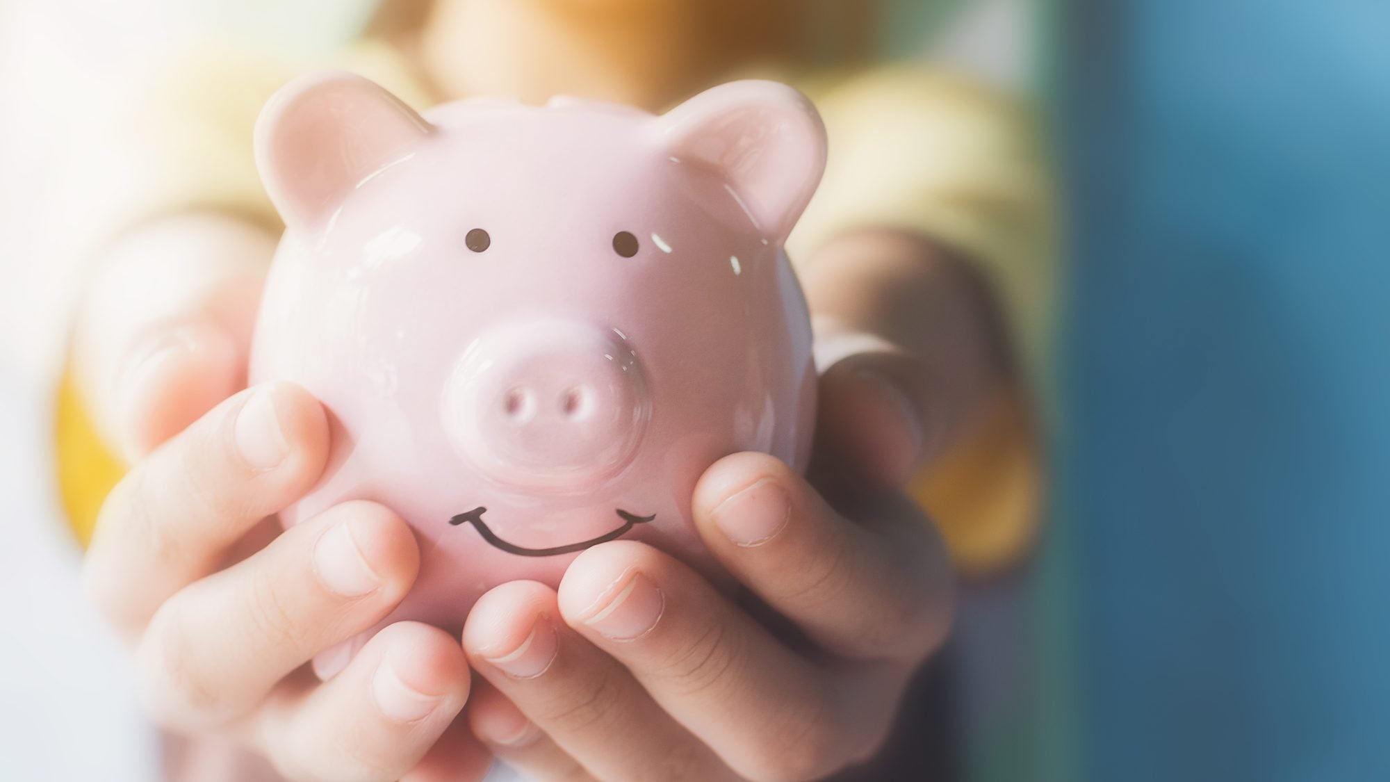 Two hands holding a pink piggy bank