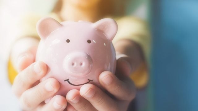 Two hands holding a pink piggy bank