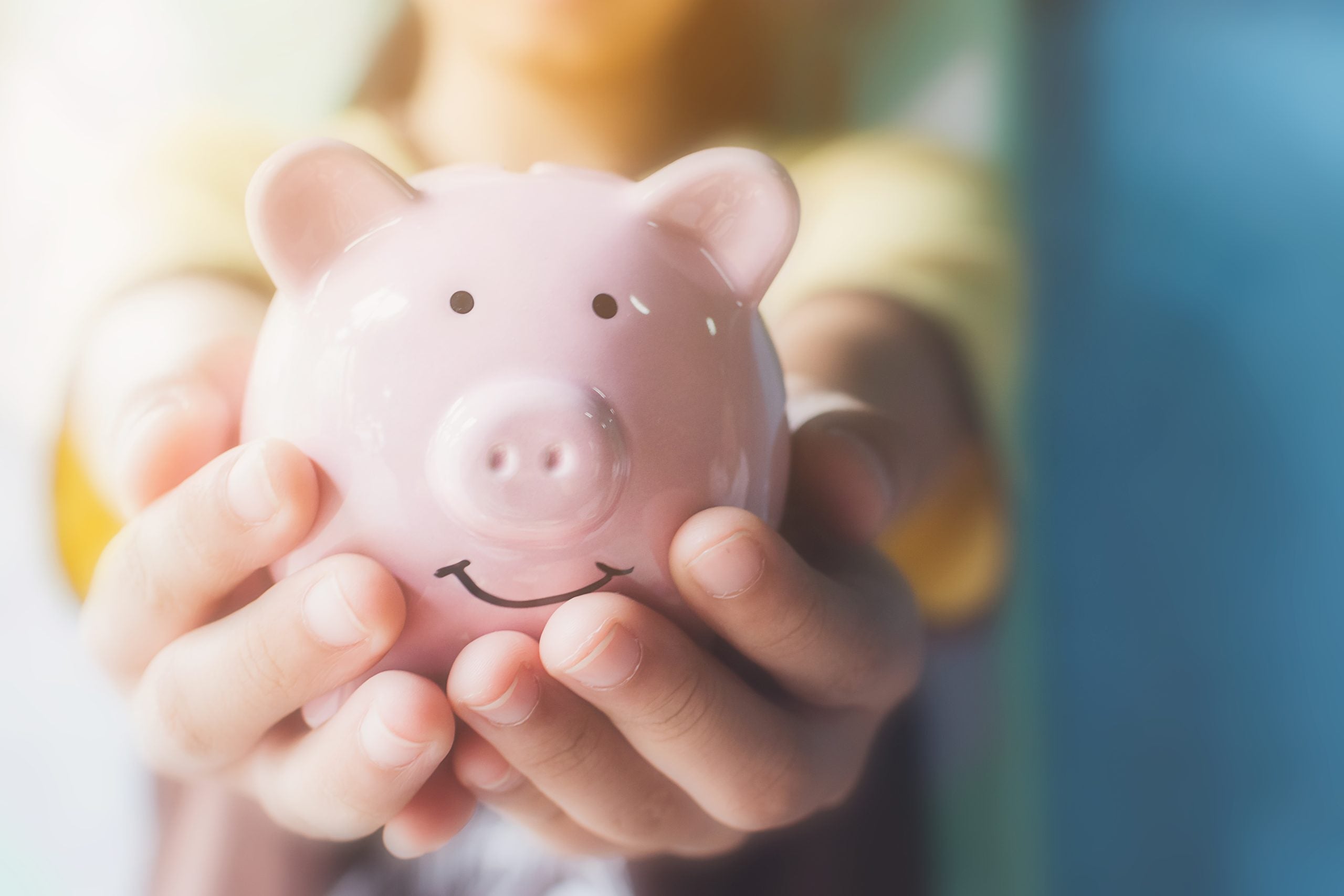 Two hands holding a pink piggy bank