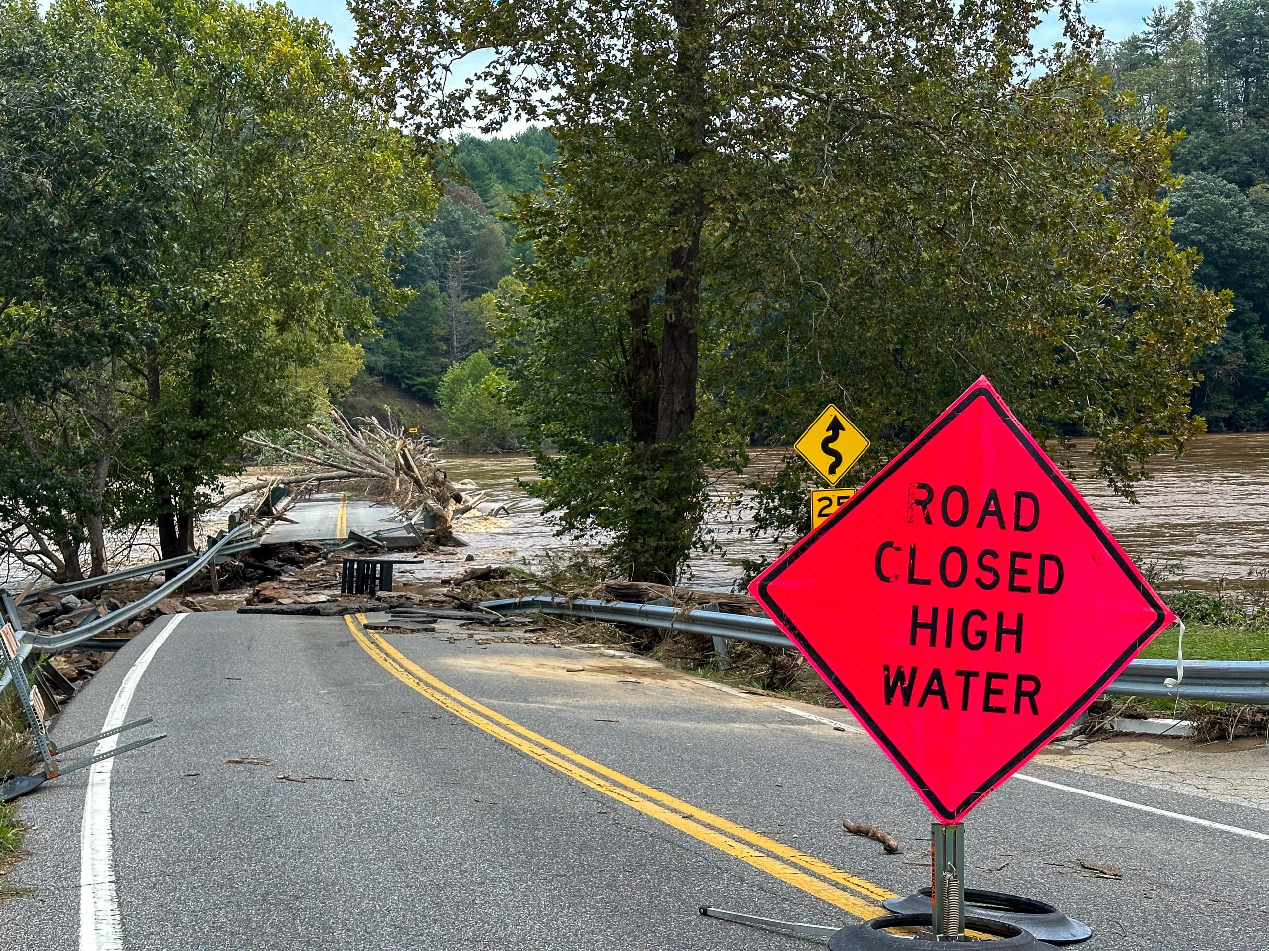 A road sign warns of road closure due to hurricane damage.