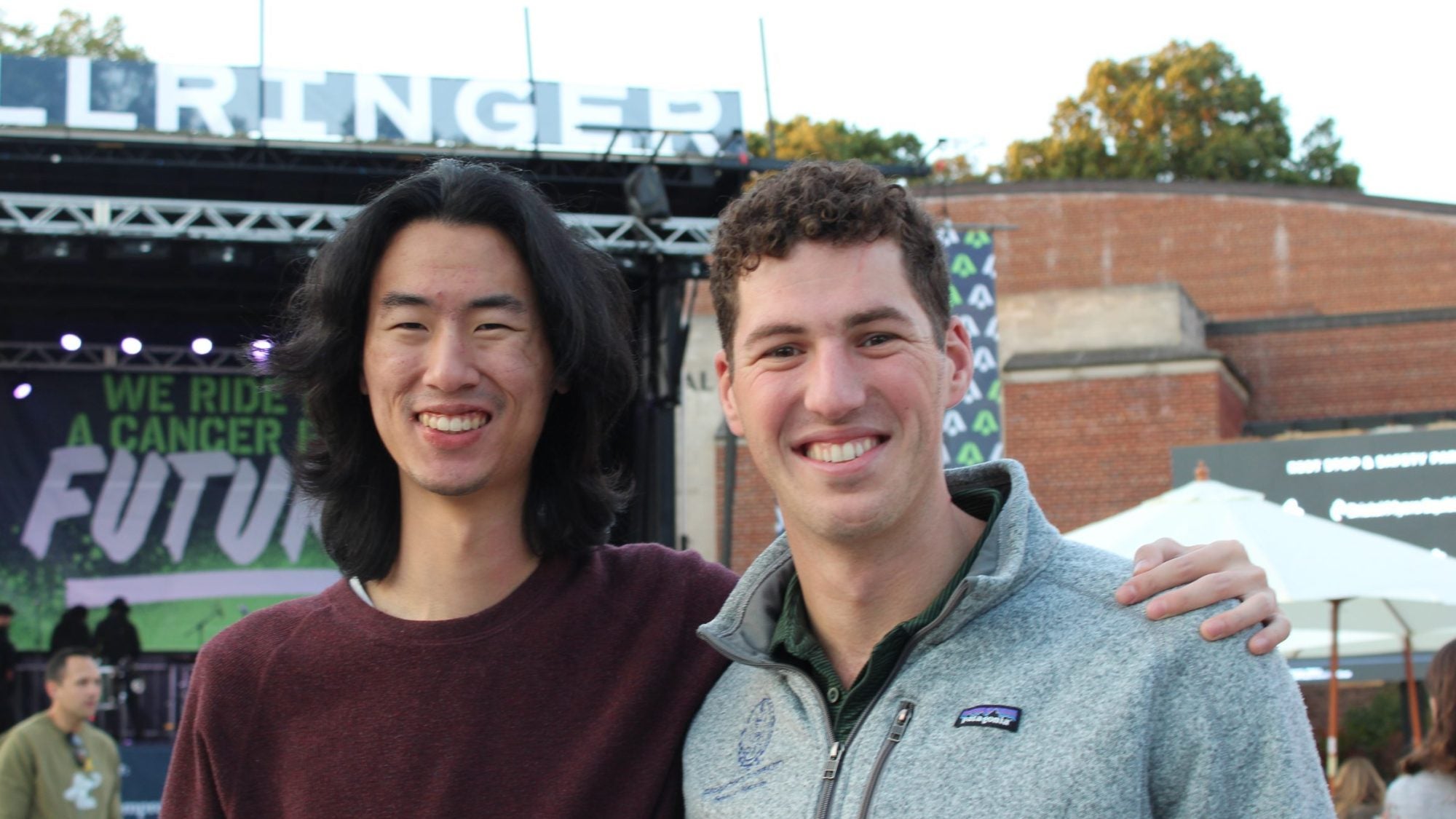 Two men pose in front of a banner that says BellRinger.