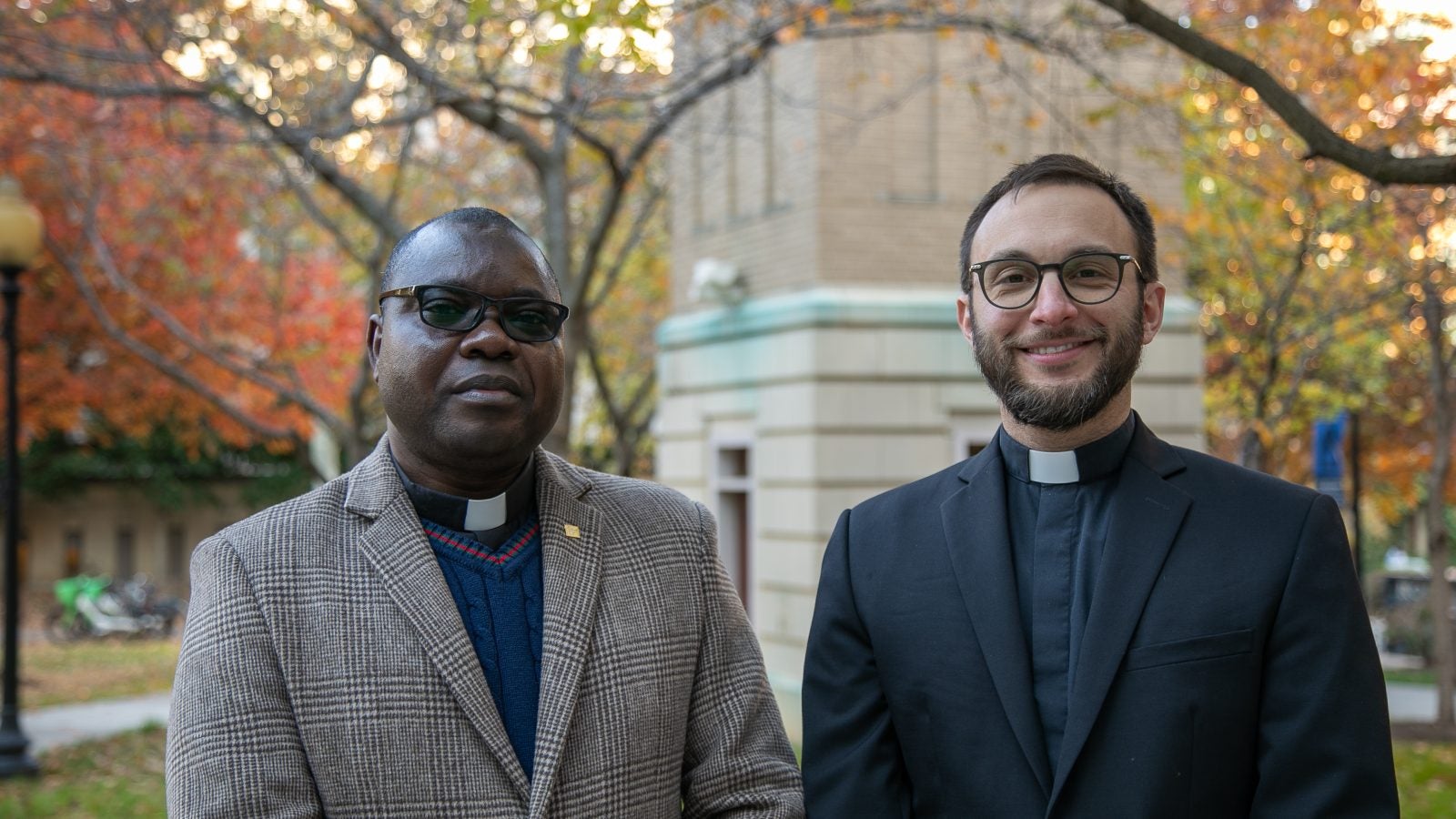 A Black priest and a white priest on an autumn day