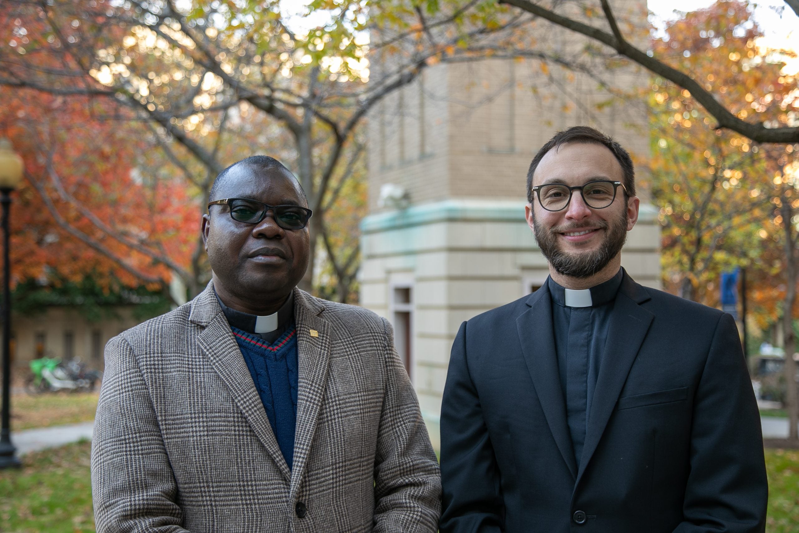 A Black priest and a white priest on an autumn day