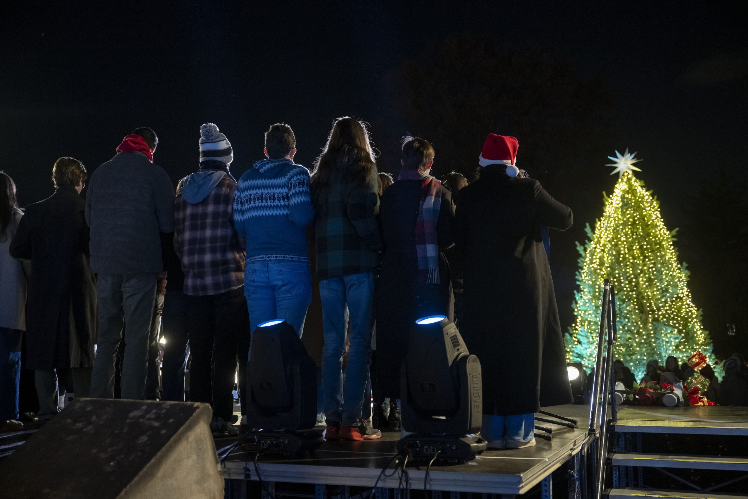 Backs of students at night facing a lit up Christmas tree