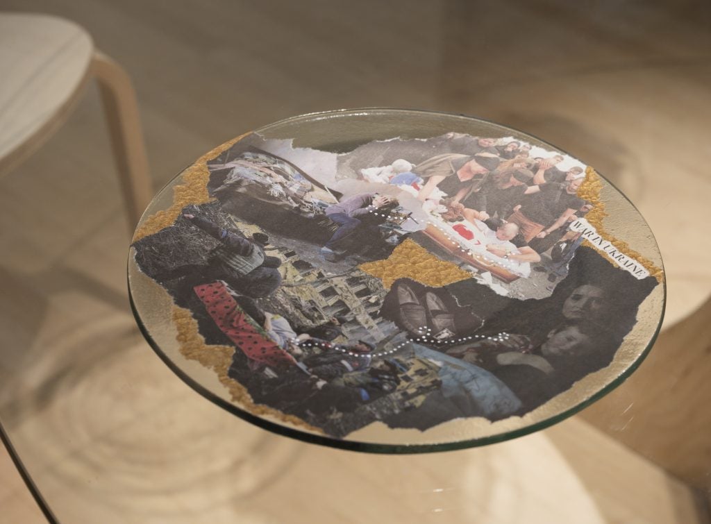 A glass plate is collaged with torn images from newspapers about the war in Ukraine.