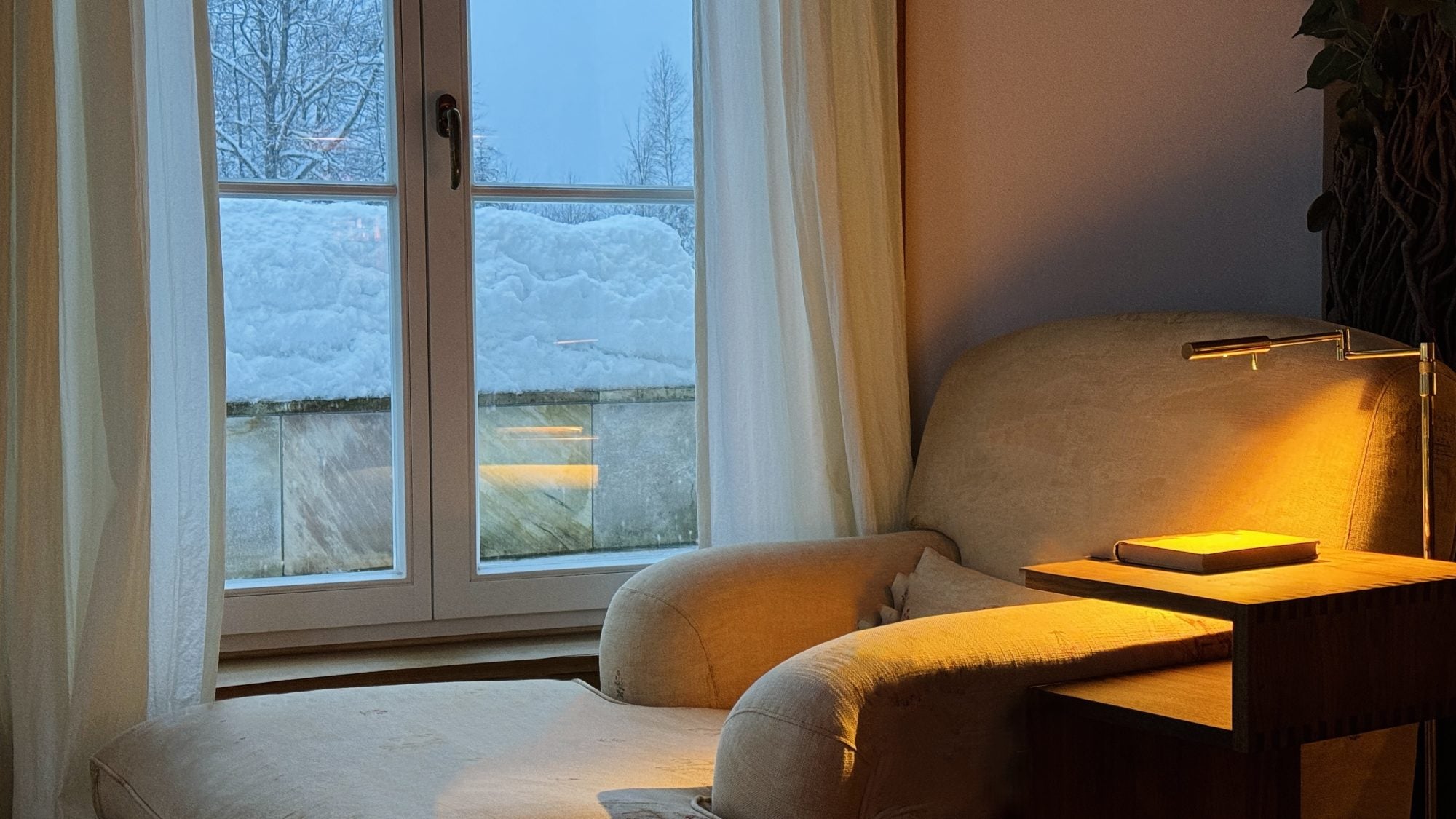 A chair next to a snowy window on a cozy winter day.