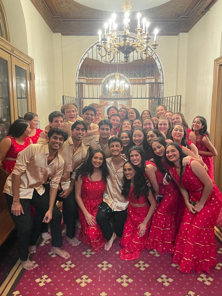 Group of performers in South Asian attire pose for a photo