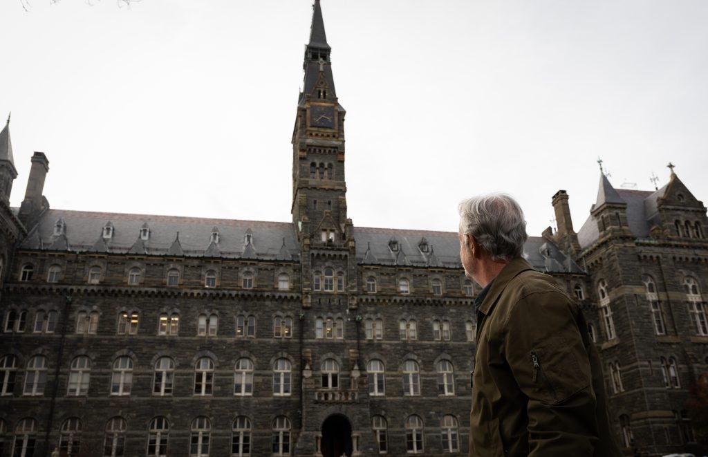 A man looks up at Georgetown's clock tower on an overcast day.